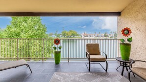 A balcony with a chair, a table, and two potted plants. -  NEW & GORGEOUS Lakefront ZEN 3 bedrooms [2 KING +1 Queen] (Phoenix)