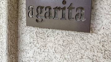 A metal plaque with the word 'agarita' mounted on a textured wall.
