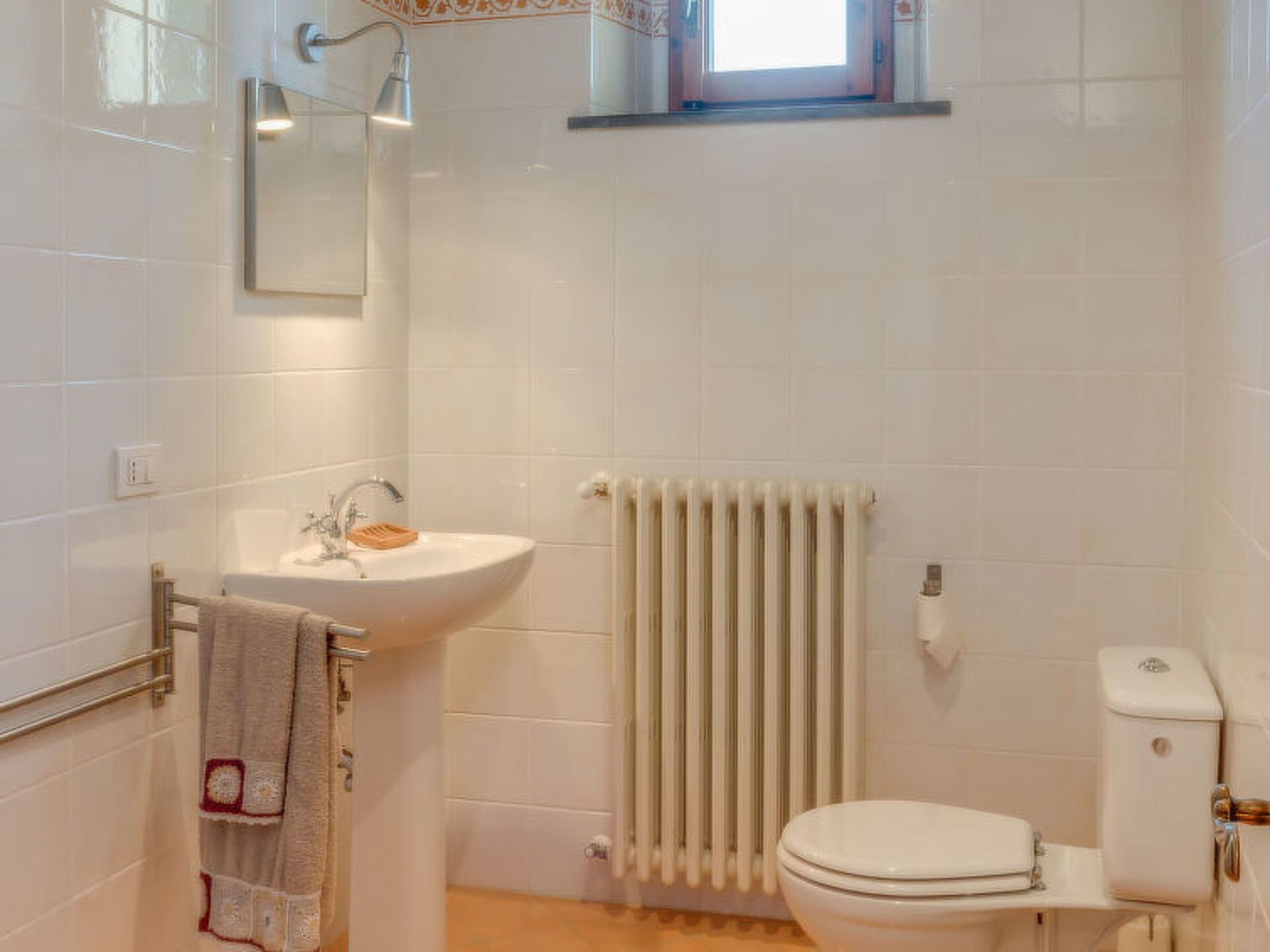 A bathroom with a sink, toilet, and radiator.