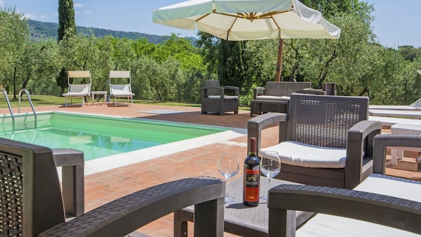Un espace aménagé au bord de la piscine, comprenant une piscine, des chaises longues et une table avec une bouteille et des verres.
