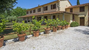 Un bâtiment à deux étages, doté d’un toit en tuiles, d’un patio couvert et d’une allée gravillonnée.