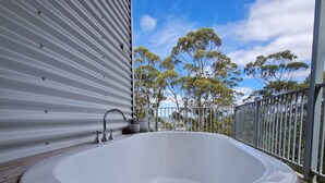 Ein Whirlpool in einer überdachten Außenbereich mit Blick auf Bäume und einen klaren Himmel.