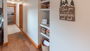 A hallway with wooden flooring, a couch, and a wall with a sign that reads "I love you to the mountains and back."