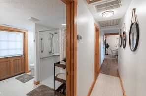 A bathroom with a shower, toilet, and a wooden bench.