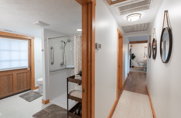 A bathroom with a shower, toilet, and a wooden bench.