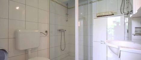 A modern bathroom with a toilet, shower, and sink.