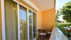 A balcony with a sliding glass door, a small round table, two chairs, and a tiled floor.