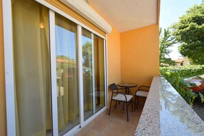 A balcony with a sliding glass door, a small round table, two chairs, and a tiled floor. - Holiday apartment mit Terrasse (Njivice)