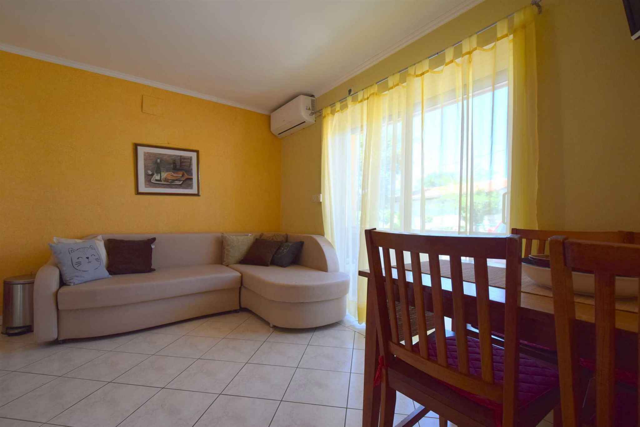 A living room with a sofa, a chair, a picture on the wall, and a window with curtains.