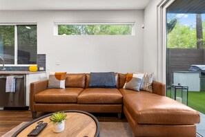 A modern living room with a brown leather sectional sofa, a wooden coffee table, and a small potted plant.
