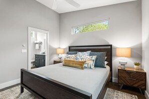 A bedroom with a large bed, two bedside tables, a nightstand, a window, and a mirror.