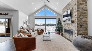 Un salón espacioso con chimenea de piedra, un ventanal grande y una zona de estar acogedora.