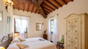 A bedroom with a large bed, a wardrobe, and a window with curtains. - Lovely apartment in villa for 6 guests with A/C, WIFI, pool, TV and terrace (Città Della Pieve)