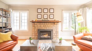 A living room with a fireplace, two sofas, a coffee table, and a bookshelf.