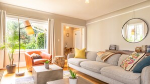 A living room with a sofa, a coffee table, a floor lamp, and a large window with curtains.