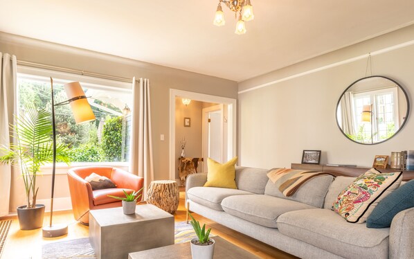 A living room with a sofa, a coffee table, a floor lamp, and a large window with curtains.