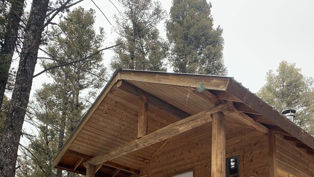 A wooden cabin with a porch, a door, and a window.