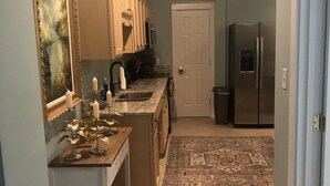 Una cocina con una isla de madera, un refrigerador y una puerta que da a otra habitación.