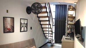 A modern interior with a staircase, a sofa, and a kitchen area.