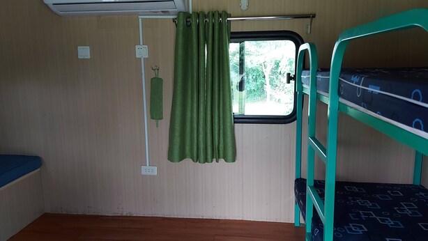A compact room with bunk beds, an air conditioning unit, a window with curtains, and a power outlet. - caravan trailer (New Taipei City)