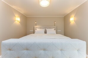 A bedroom with a large bed, two wall-mounted lights, and a ceiling light. - Appartement Anker-perle (Sylt)