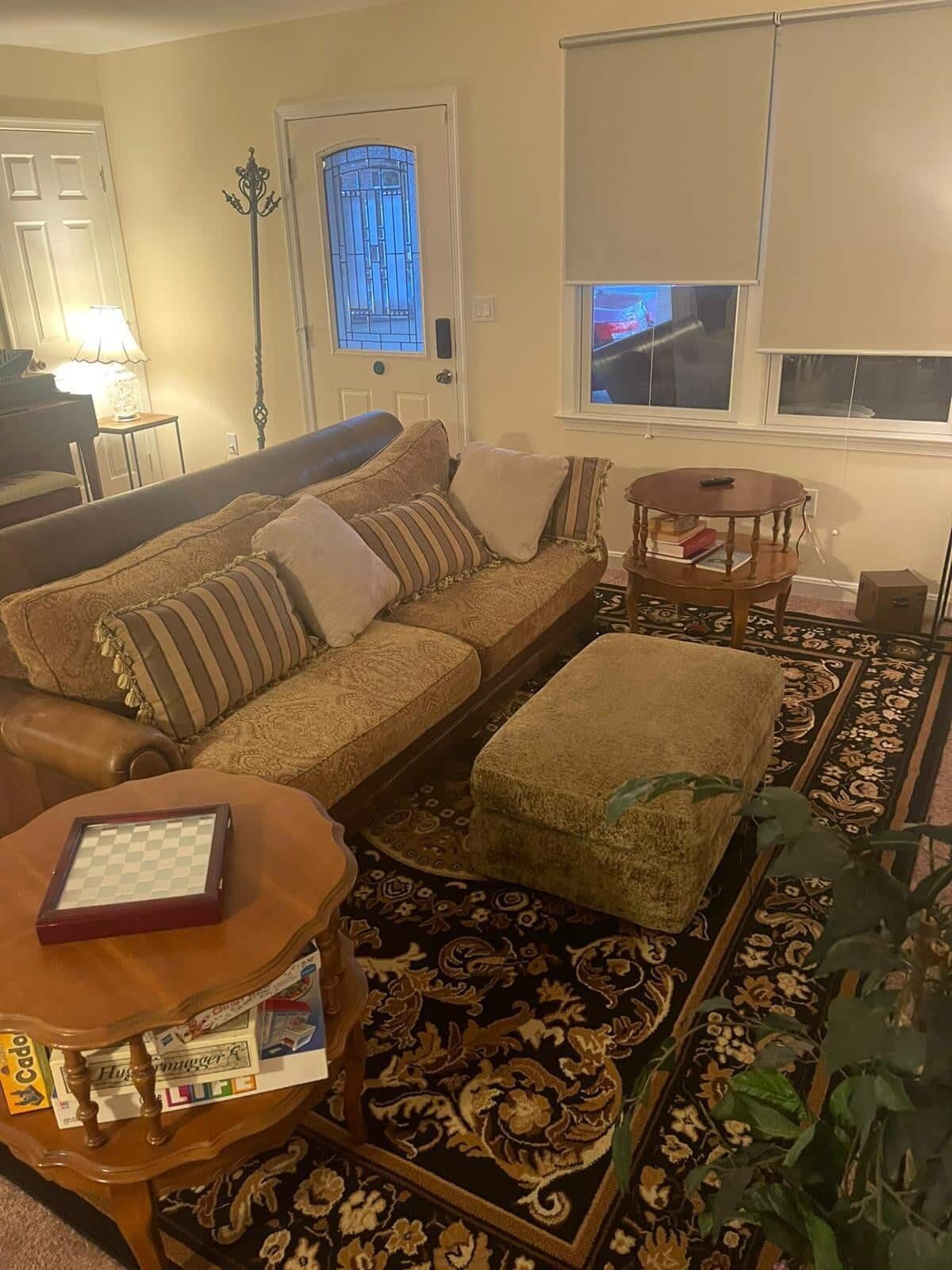 Uma sala de estar com sofá, apoio para os pés, mesa de centro e tapete.