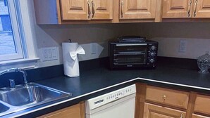 Eine Küche mit Holzausstattung, einem Geschirrspüler, einem Toaster und einem gefliesten Boden.