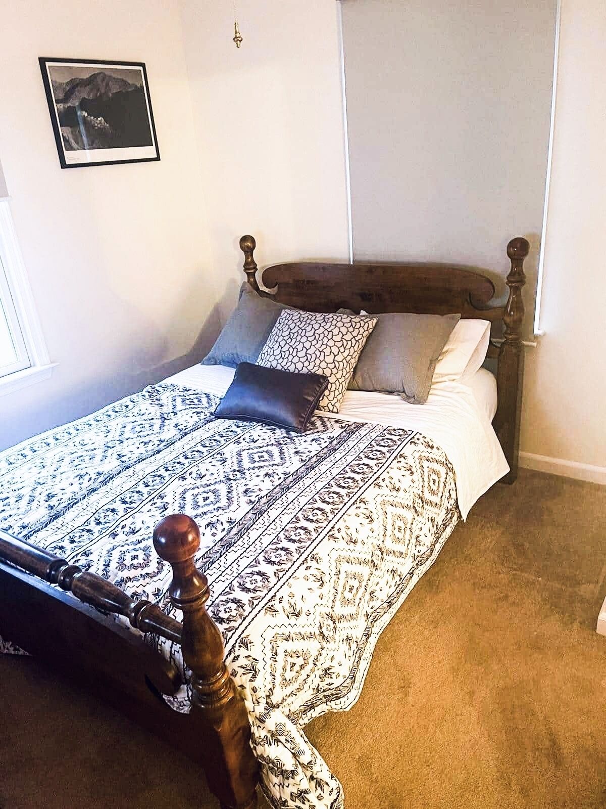 Une chambre à coucher avec un cadre de lit en bois, une couvre-lit à motifs et une petite table de chevet.