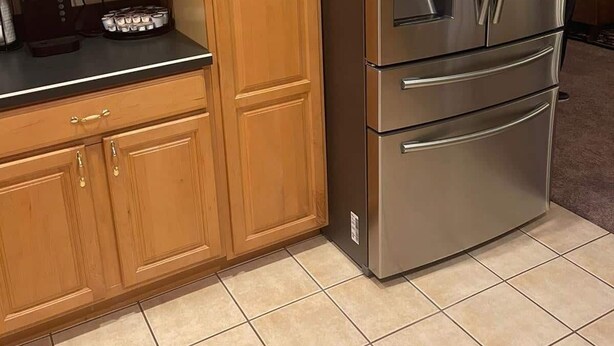 Eine Küche mit Holzausstattung, einem Edelstahlkühlschrank, einer Kaffeemaschine und einem Wasserspender.