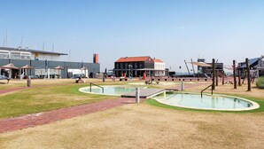 Una piazza pubblica con una piscina, panchine e un edificio dal tetto rosso.