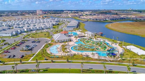Zona residencial con una amplia piscina, estacionamiento y un río al fondo.