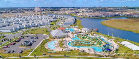 A residential area with a large swimming pool, a parking lot, and a river in the background.