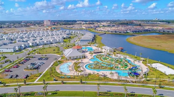 A residential area with a large swimming pool, a parking lot, and a river in the background.
