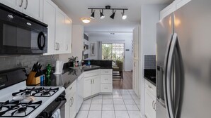 Een moderne keuken met witte kasten, een zwart aanrecht, roestvrijstalen apparatuur en een centraal eiland.