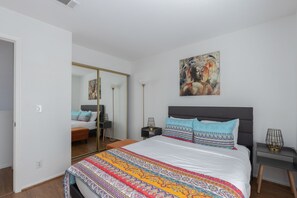 Une chambre à coucher avec un grand lit, un miroir, un tableau et une table de chevet.
