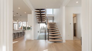 A spacious interior with a modern staircase, a kitchen area, and a view to the outside. - Rehoboth Beach Ocean Block Private Pool Parking Clean (Rehoboth Beach)