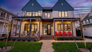A two-story house with a covered porch, a front door, and a small front yard with a pathway leading to the entrance. - Rehoboth Beach Ocean Block Private Pool Parking Clean (Rehoboth Beach)