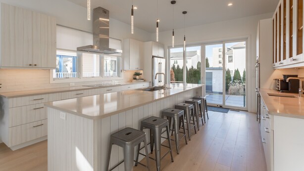 A modern kitchen with a large island, bar stools, and pendant lighting. - Rehoboth Beach Ocean Block Private Pool Parking Clean (Rehoboth Beach)