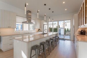Una cocina moderna con una isla grande, taburetes de bar e iluminación colgante.