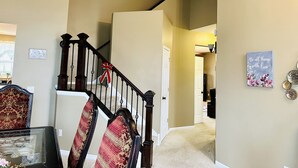 A staircase with a red and white ribbon, a chandelier, and a wall with a motivational quote. - 5 Bedroom Private Villa with Peloton Bike (Shakopee)