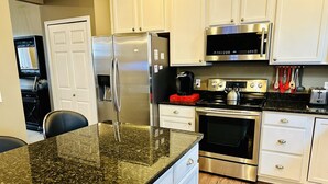 A modern kitchen with stainless steel appliances, white cabinetry, and a granite countertop. - 5 Bedroom Private Villa with Peloton Bike (Shakopee)