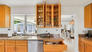 A modern kitchen with wooden cabinets, a stainless steel dishwasher, and a built-in wine rack. - 4 Bedroom Pool Home - Walk to the Beach! (West Palm Beach)