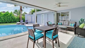 An outdoor patio with a pool, a dining table with chairs, and a sofa with cushions. - 4 Bedroom Pool Home - Walk to the Beach! (West Palm Beach)