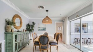 A dining area with a wooden table, six chairs, a hanging light fixture, a green cabinet, and a large mirror on the wall. - 4 Bedroom Pool Home - Walk to the Beach! (West Palm Beach)