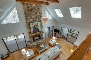 Un loft espacioso con chimenea de piedra, muebles blancos y amplias ventanas.