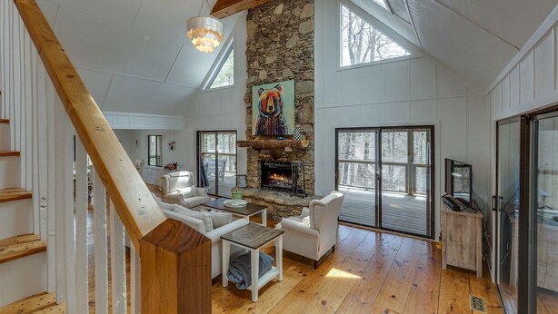 Un loft espacioso con chimenea de piedra, vigas de madera y ventanas grandes.