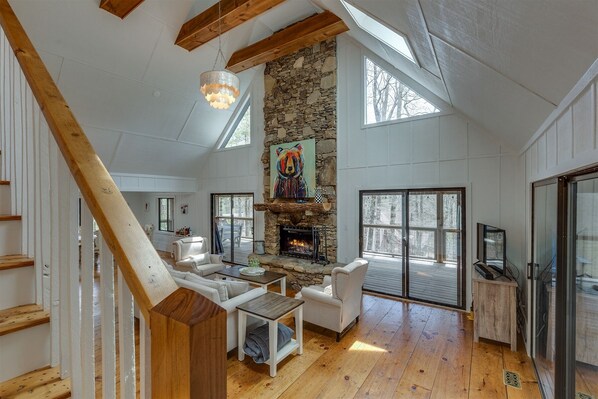 A spacious loft with a stone fireplace, wooden beams, and large windows. - Everything You Need, Nothing You Don't | Bear Necessities (Highlands)