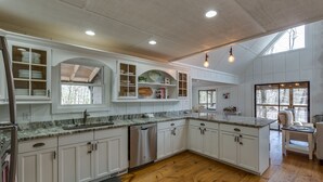 Una cocina amplia con armarios blancos, encimeras de granito y piso de madera.