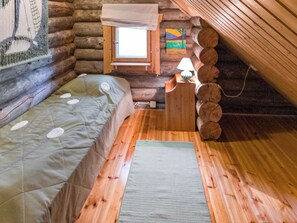 A log cabin bedroom with a bed, a small table with a lamp, and a window. - Lomaperä by Interhome (Ylläsjärvi)