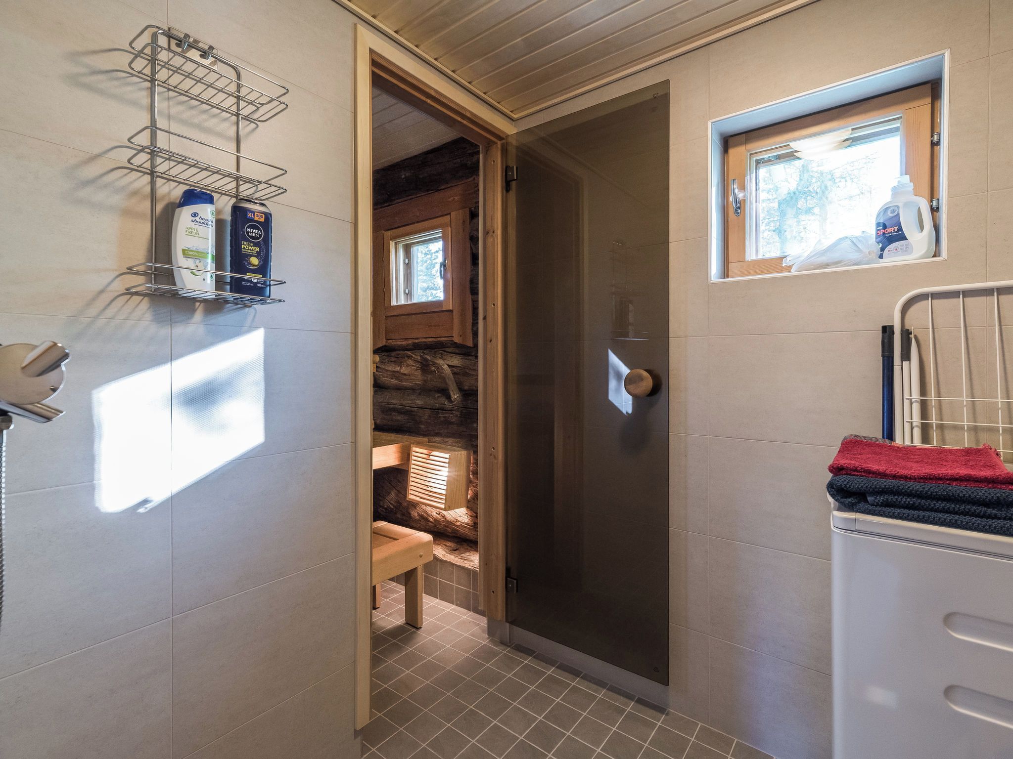 Une salle de bain avec une douche, un porte-serviettes et une étagère contenant des articles de toilette.